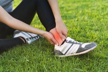 Genç Asyalı kadın, spor koşusunda bileğini burkmuş.