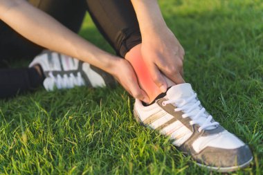 Egzersiz ve sağlıklı konsept. Genç Asyalı kadın spor koşusunda bileğini burkmuş. Seçici odaklanma..