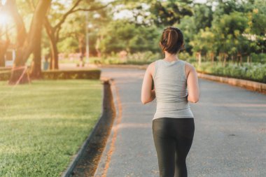 Egzersiz ve sağlıklı konsept, spor giyim saatinde parkta koşan Asyalı genç bir koşucunun arkası, seçici odaklanma..