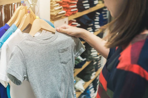 Young asian woman shopping trendy kid clothes for her\'s son in shopping mall, Selective focus.