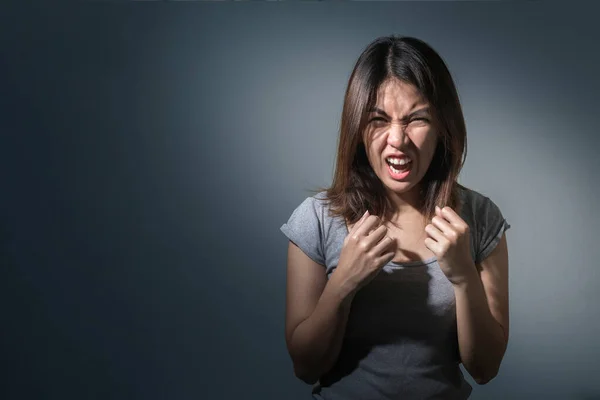 Emotion concept, Portrait of angry cute asian woman standing looking at camera with grey clothes on a dark blue background