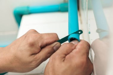 Tesisat tamiri, Asyalı adam banyodaki PVC borularını kesmek için testere kullanıyor..