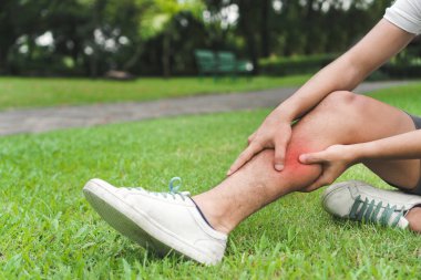 Asyalı genç adam spor koşusunda bacağını burkmuş. Seçici odaklanma, egzersiz ve sağlıklı konsept..