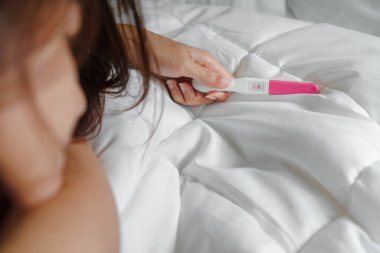 Hamilelik testi tutan genç Asyalı kadın pozitif sonuç, sağIık ve sağlıklı konsept, kürtaj sorunu, seçici odaklanma.