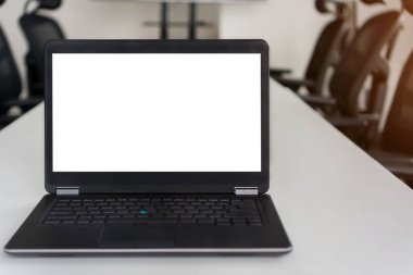 Toplantı odasındaki çalışma masasında boş beyaz ekran ile dizüstü bilgisayarın ön görüntüsü, kırpma yolu ile seçici odak oluşturun.