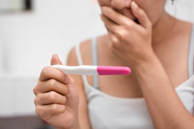 Hamilelik testi tutan Asyalı genç bir kadın ve banyosu, sağlığı ve sağlıklı konsepti, kısırlık sorunu, seçici odaklanma sorunu sonucu şok olmuş..
