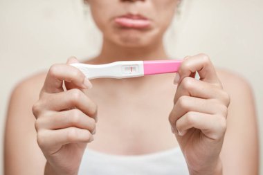 Hamilelik testi tutan mutsuz genç Asyalı kadın tuvaletinde, sağlığında ve sağlıklı konseptinde, kısırlık probleminde, seçici odak noktasında negatif sonuç veriyor..