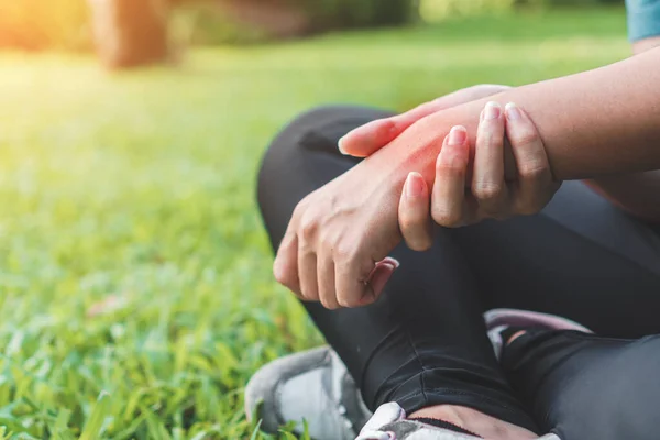 Genç Asyalı kadın kaza geçirdi ve bileğini tutarak bileğini burktu spor koşusunda burkuldu, seçici odaklanma.