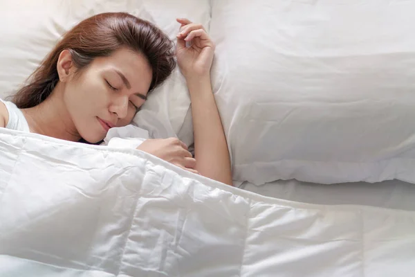 Young asian woman sleeping alone on white pillow on bed in bedroom on morning time, copy space.