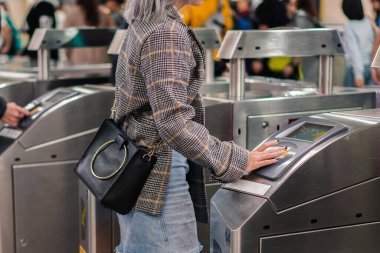 İnsanlar tren istasyonunun girişinde bilet dokunuşu ve ödeme yapıyorlar..