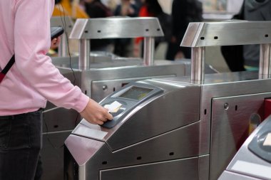 İnsanlar tren istasyonunun girişinde bilet dokunuşu ve ödeme yapıyorlar..
