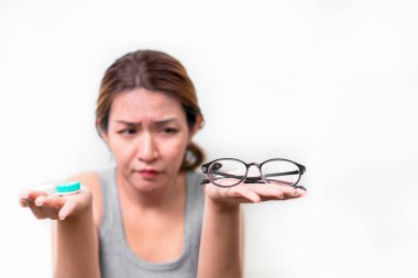 Beyaz arka planda gözlük ve kontak lens tutan Asyalı kadın, gözlük, miyop ve görme sorunu kavramı üzerine seçici odaklanma.