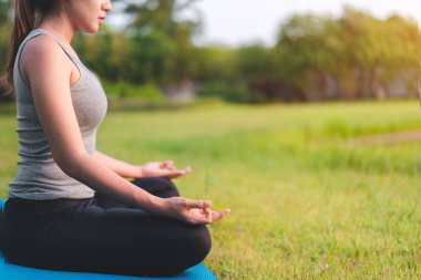 Asyalı kadın meditasyon yapıyor ve lotusta oturuyor. Parkta poz veriyor, Sağlıklı ve Yoga Kavramı, Zihin-Vücut Geliştirme Konsepti, Seçici Odaklanma, Boşluğu Kopyalama.