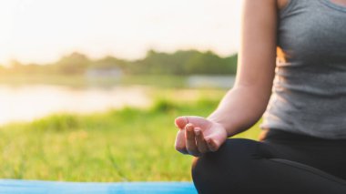 Asyalı kadın meditasyon yapıyor ve lotusta oturuyor. Parkta poz veriyor, Sağlıklı ve Yoga Kavramı, Zihin-Vücut Geliştirme Konsepti, Seçici Odaklanma, Boşluğu Kopyalama.