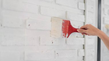 Evindeki boya fırçasıyla iç duvarı boyayan kadının elini kapat..