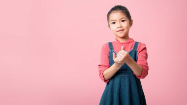 Asyalı kız elini sabunla yıkıyor, temizlik için. Pembe arka planda izole edilmiş, kırpma yolu, sağlık sigortası ve enfeksiyon konseptiyle..