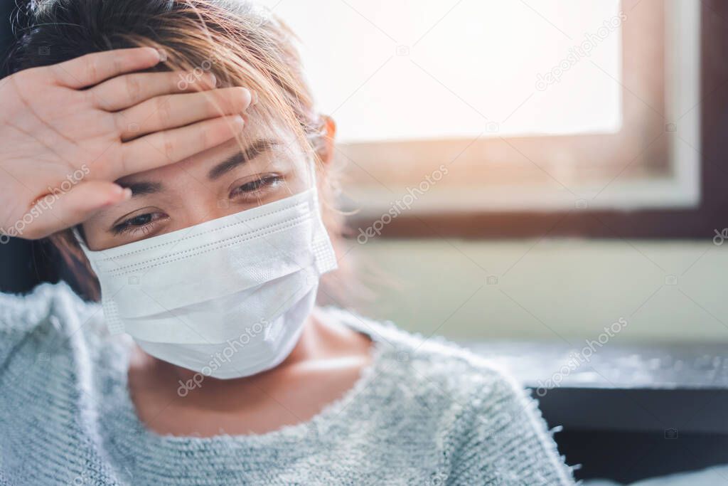 Sick asian woman have hight fever flu and touch her head for checking temperature on bed in bedroom, Medical and health concept, Selective focus.