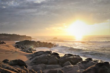 Gün batımında Atlantik Okyanusu 'nun güneşli sahillerinde. Kumsal, kumdaki ayak izleri, taşlar, zümrüt dalgalar. Portekiz. Porto