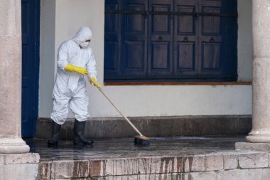 Güney Amerika 'da koronavirüs salgını sırasında Cusco, Peru' da sokak dezenfeksiyonu. Beyaz üniformalı bir adam eski kasabada yerleri temizliyor.