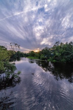 Sakin nehir suyuna yansıyan mavi saat bulutları. (Charles River, Watertown, Massachusetts, ABD)