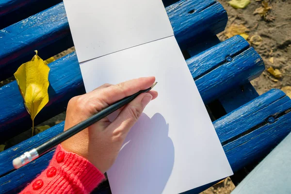 Um bloco de notas em branco para planejamento, resumindo. A mão segura o lápis. Ela vai desenhar ou manter um bloco de notas . — Fotografia de Stock