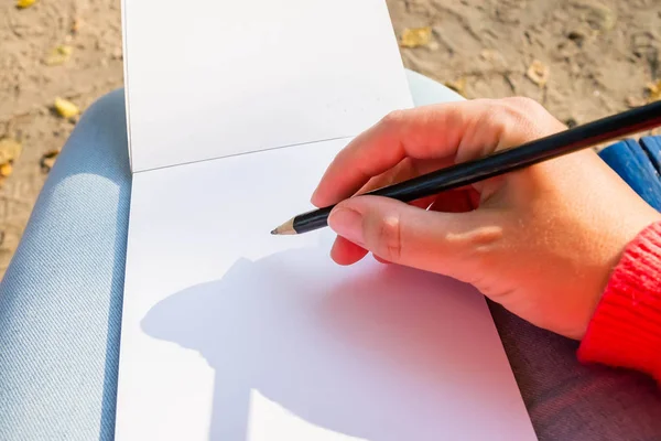 Ett tomt anteckningsblock för planering, summering. Handen håller pennan. Hon kommer att rita eller behålla ett anteckningsblock. — Stockfoto