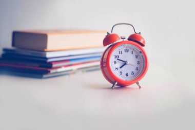 Kitap arkaplanındaki turuncu mekanik saat. Beyaz arka grup