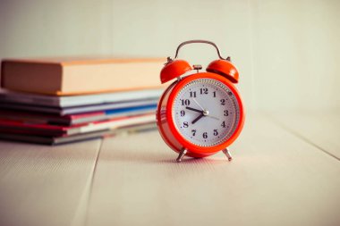 Kitap arkaplanındaki turuncu mekanik saat. Beyaz arka grup