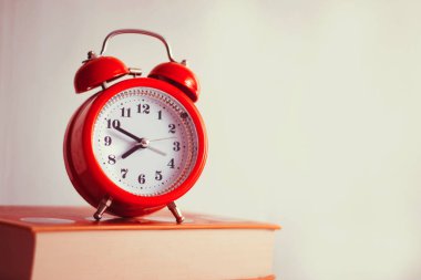 Kitap arkaplanındaki turuncu mekanik saat. Beyaz arka grup