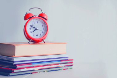 Kitap arkaplanındaki turuncu mekanik saat. Beyaz arka grup