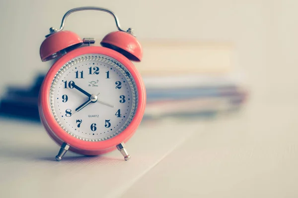 Kitap arkaplanındaki turuncu mekanik saat. Beyaz arka plan. Odaklanamayan kitaplar. Öğrenme konsepti. Kitap okuma zamanı. Eski moda. Kişilik gelişimi. Bilişsel fonksiyonların gelişimi.