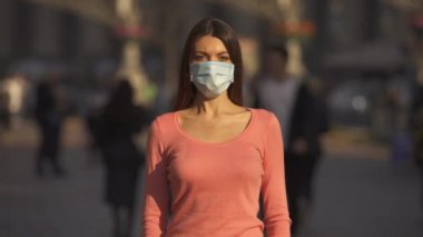 Tıbbi maskeli kız kalabalığın içinde duruyor.