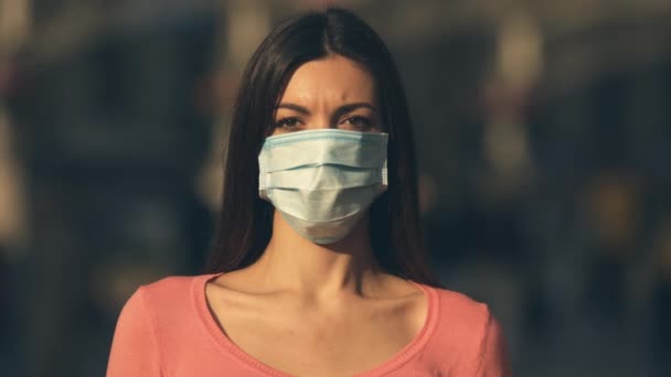 医者の顔のマスクをした若い女性が群衆の中に立っている — ストック動画