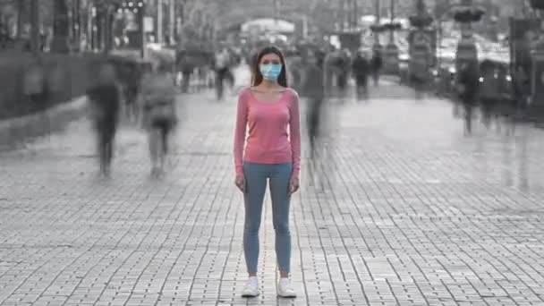 顔のマスクをした女の子が混雑した通りに立っている 時間の経過 — ストック動画