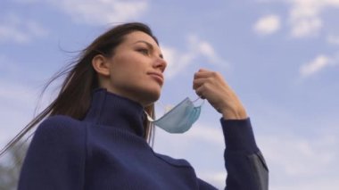 Dışarıdaki tıbbi maskeyi çıkaran çekici kadın. yavaş çekim
