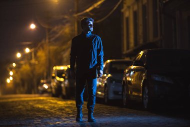 Adam yolda dikiliyor. İyi akşamlar gece. Telefoto mercek görüntüsü