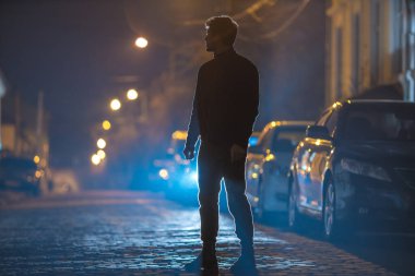 Adam taş yolda dikiliyor. İyi akşamlar gece. Telefoto mercek görüntüsü