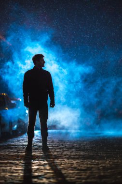 Adam duman sokağında duruyor. İyi akşamlar gece. Telefoto mercek görüntüsü