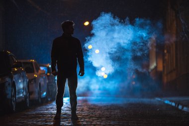 Adam duman sokağında duruyor. İyi akşamlar gece. Telefoto mercek görüntüsü