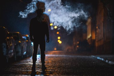 Adam duman bulutunun yanında duruyor. Akşam vakti.