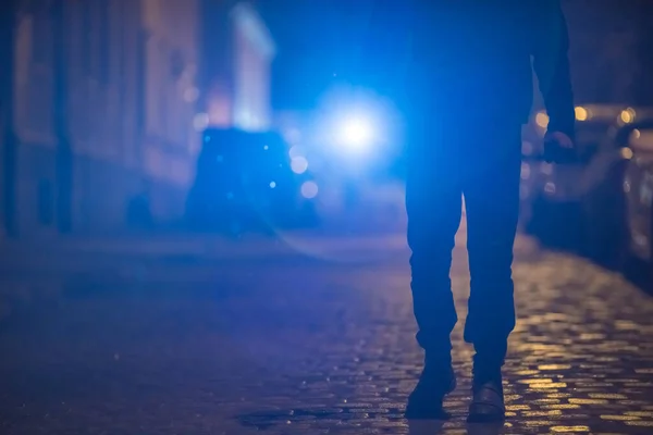 Parlak bir feneri olan adam yolda duruyor. Akşam vakti.