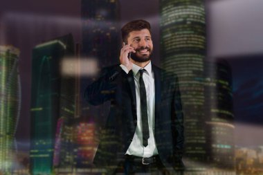 Pencerenin yanındaki iş adamı telefonu bir gökdelenin arka planında.