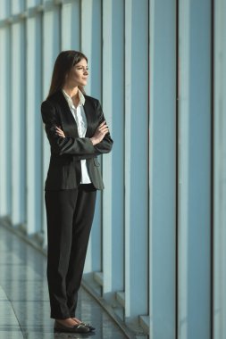 İş kadını panoramik pencerenin yanında duruyor.