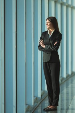 İş kadını panoramik pencerenin yanında duruyor.