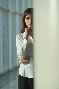 Ciddi kadın sütunun yanında duruyor.