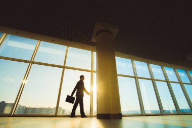 Adam elinde bir bavulla gün ışığında yürüyor.