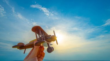 Gün batımının arka planında tahta bir uçak olan el.