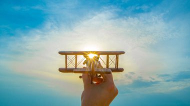 Parlak güneşin arka planında tahta bir uçak olan el.