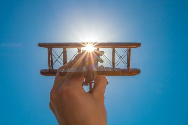 Açık gökyüzünün arka planında oyuncak bir uçağı olan el.