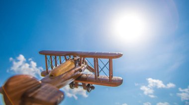Ahşap uçak parlak bir güneşin arka planında uçar.